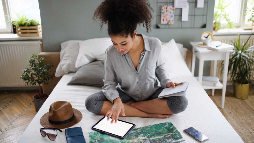 chica con tablet, mapa y un sombrero planeando un viaje