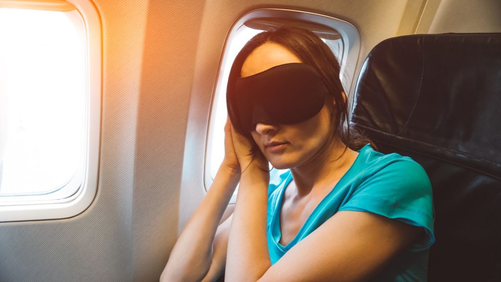 Mujer durmiendo en un avión con antifaz